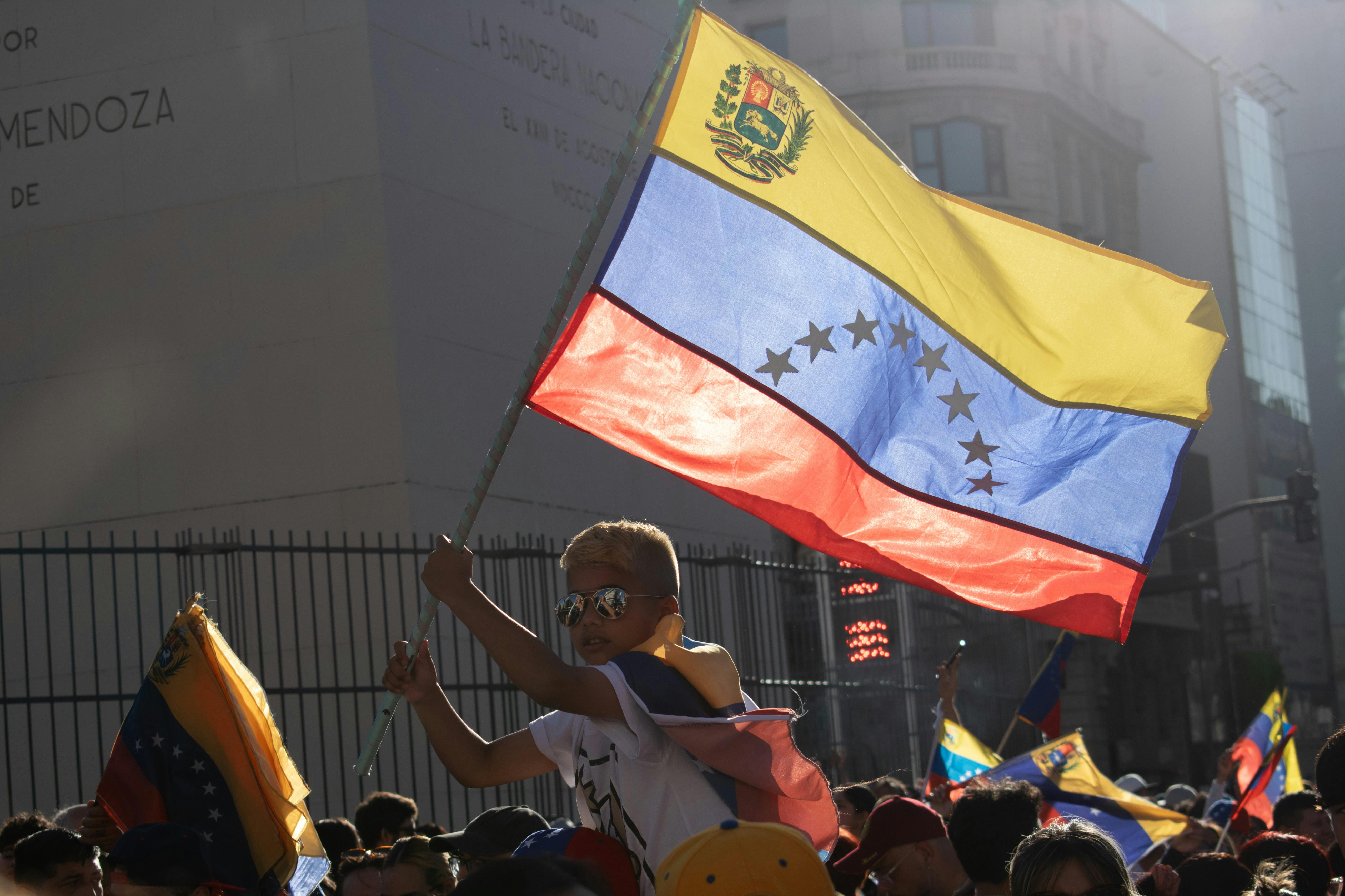 Un niño sostiene la bandera de Venezuela durante una protesta en Buenos Aires, Argentina. La crisis venezolana ha llevado a cientos de miles de niños a crecer lejos de su país. (Foto: Pexels/Renan Braz)