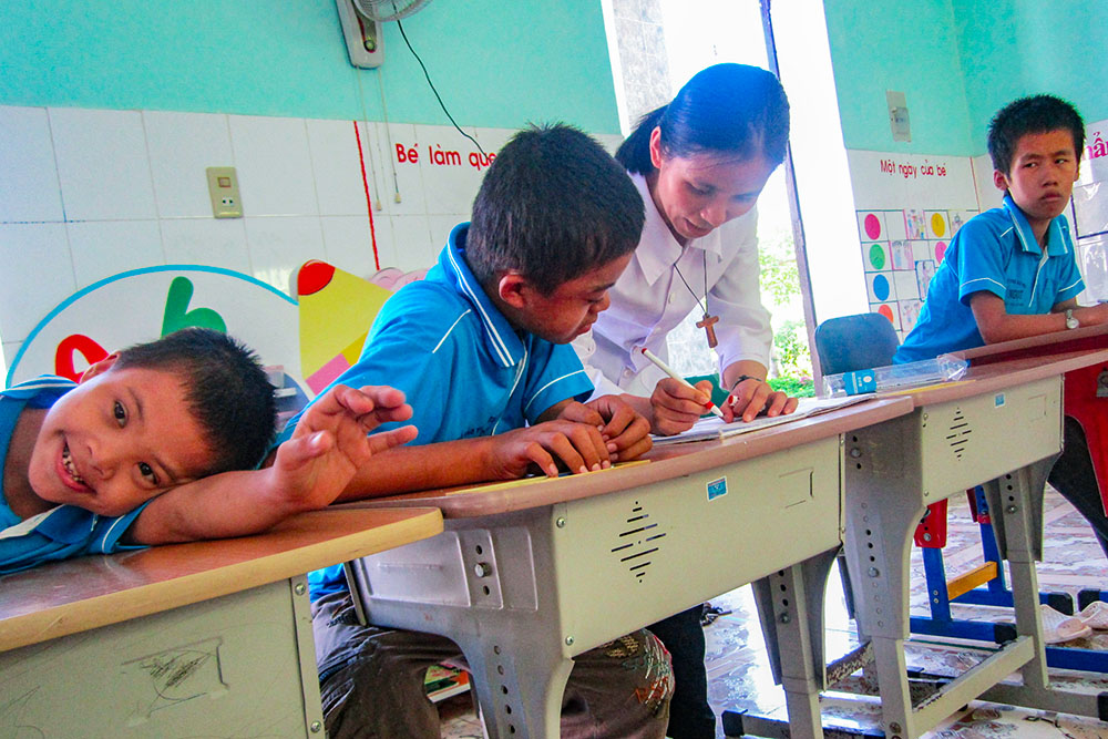 Sr. Mary Bach Thi Loan teaches a child how to write at the center run by the Daughters of Mary of the Immaculate Conception in Hue, Vietnam, on Sept. 22, 2025. (Joachim Pham)