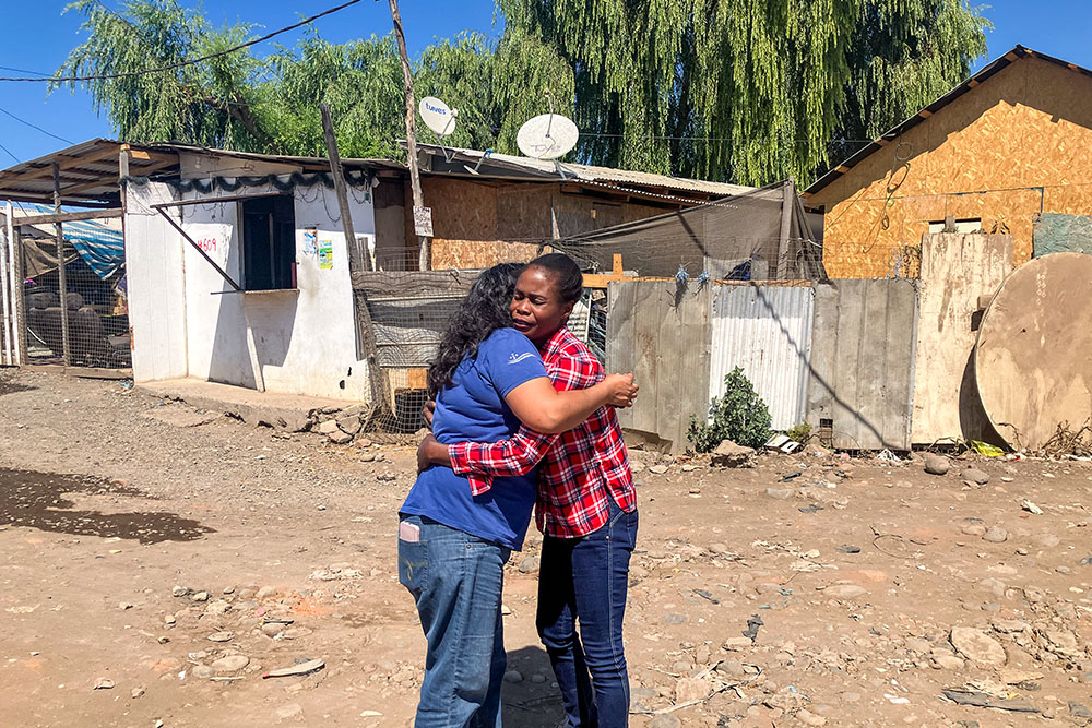 Sr. Ana María Carvajal greets Evena Promesse in the streets of an irregular settlement populated by Haitian immigrants in Curicó, Chile. The settlement's residents face an uncertain future as Chile's new government has promised to expel migrants without legal status. Since arriving in 2022, Promesse has not been able to receive the proper immigration papers. (GSR photo/David Agren)