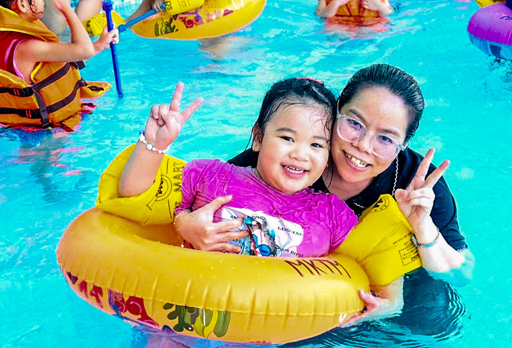 Sr. Mary Nguyen Hong Vy poses with a child after a water safety lesson at a pool in Hue, Vietnam, on July 10, 2026. (Joachim Pham)