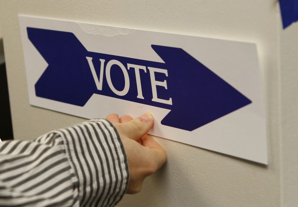 An election worker puts up a sign at a polling station in McLean, Va. (OSV News/Reuters/Kevin Lamarque)