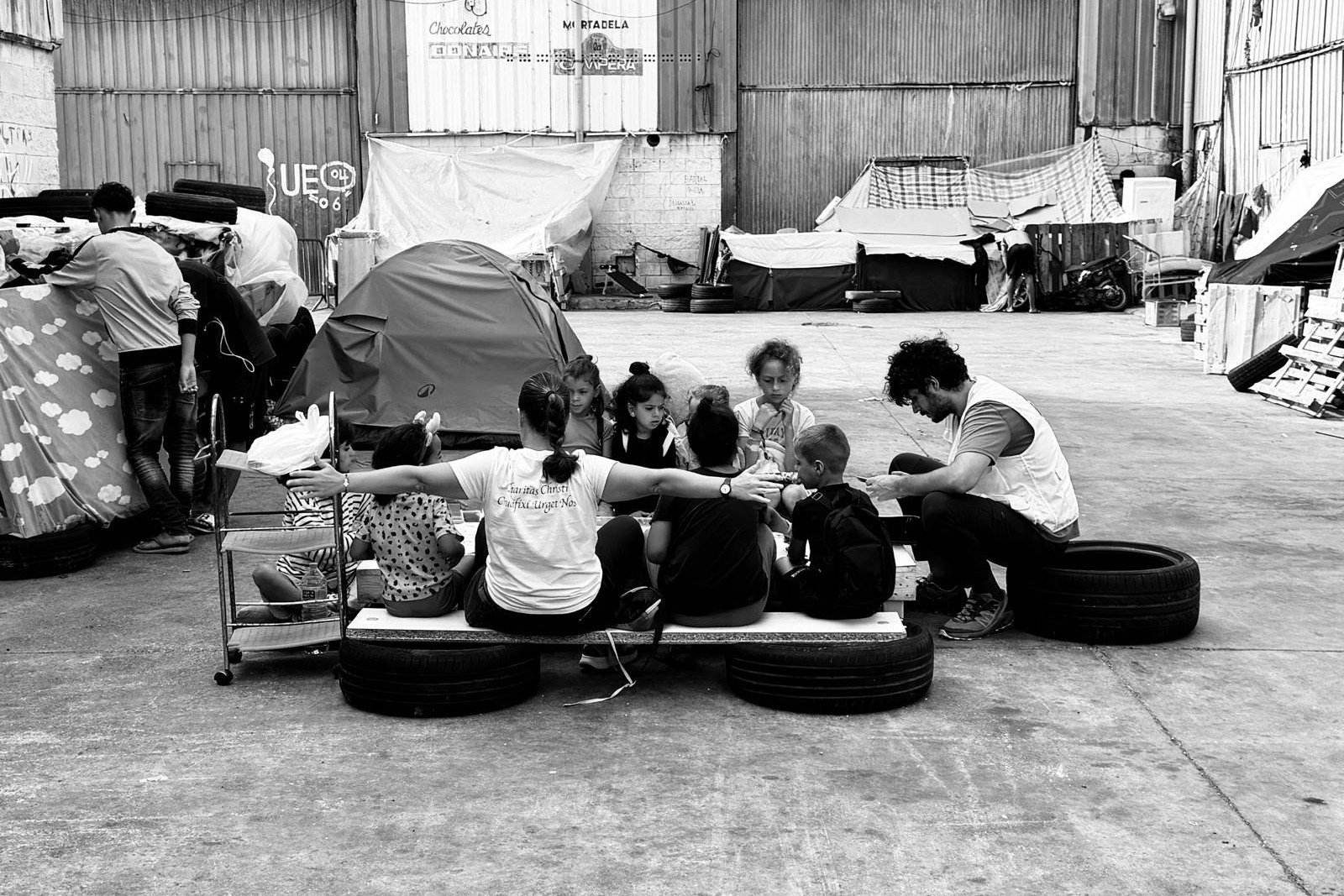 Menores migrantes no acompañados permanecen sentados en una zona de carpas en Ceuta, donde reciben atención de personal de las religiosas y de la Cruz Roja. (Foto: cortesía Mari Carmen Sapiña)