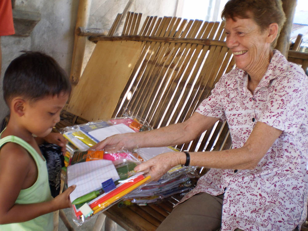 Sr. Patricia Fox distributes educational materials to children in Hacienda Luisita, a sugar cane plantation in Tarlac, north of Manila, Philippines. (Courtesy of Patricia Fox)