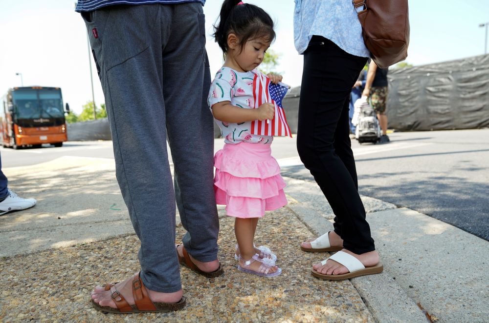 A girl holding a U.S. flag waits with her parents Aug. 24, 2021, at a processing center for refugees evacuated from Afghanistan at the Dulles Expo Center near Dulles International Airport in Chantilly, Virginia. (CNS/Reuters/Kevin Lamarque)