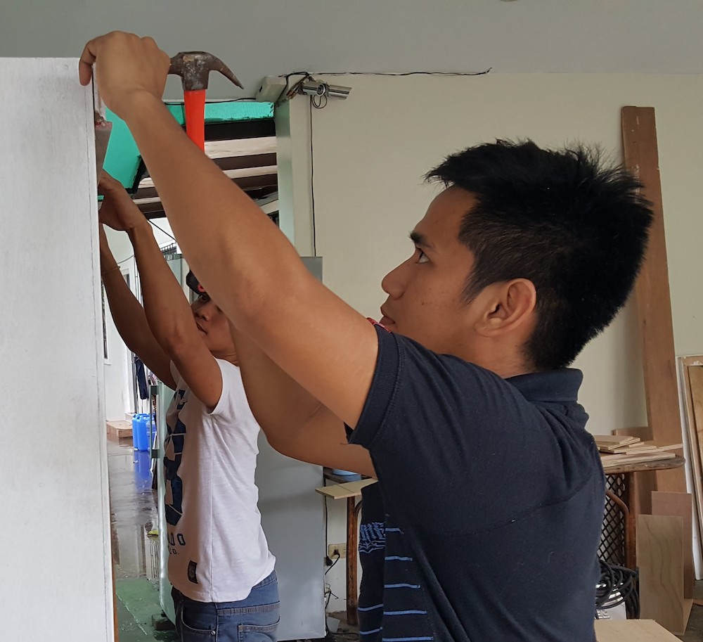 Teen boys and young men in the Second Chance program help build a door for use in the School of Life home in November 2017