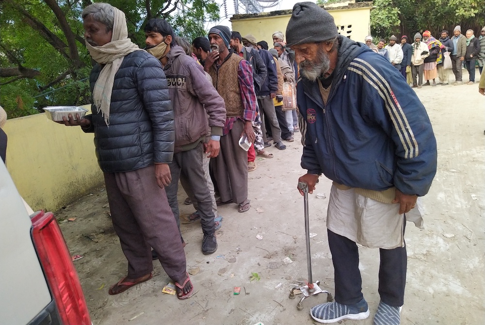 People in need line up when the vehicle loaded with food from Food for Hungry reaches the distribution area at banks of Yamuna River (Jessy Joseph)