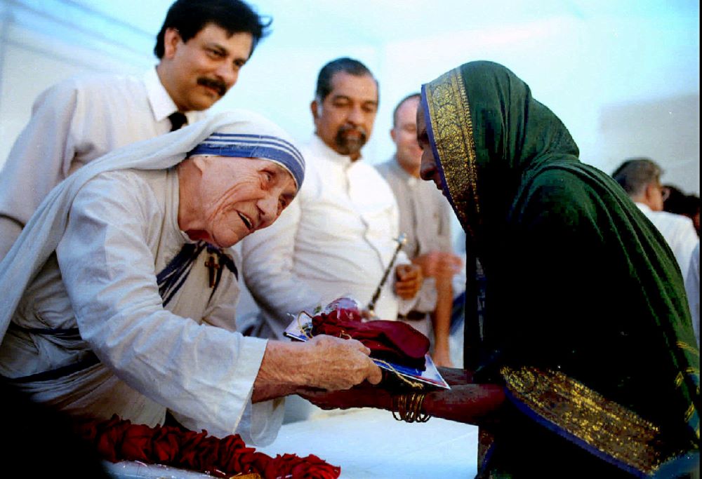 Mother Teresa of Kolkata, India, presents documents for a new house to a villager in 1994 in Mumbai, formerly Bombay. (CNS/Reuters/Luciano Mellace)