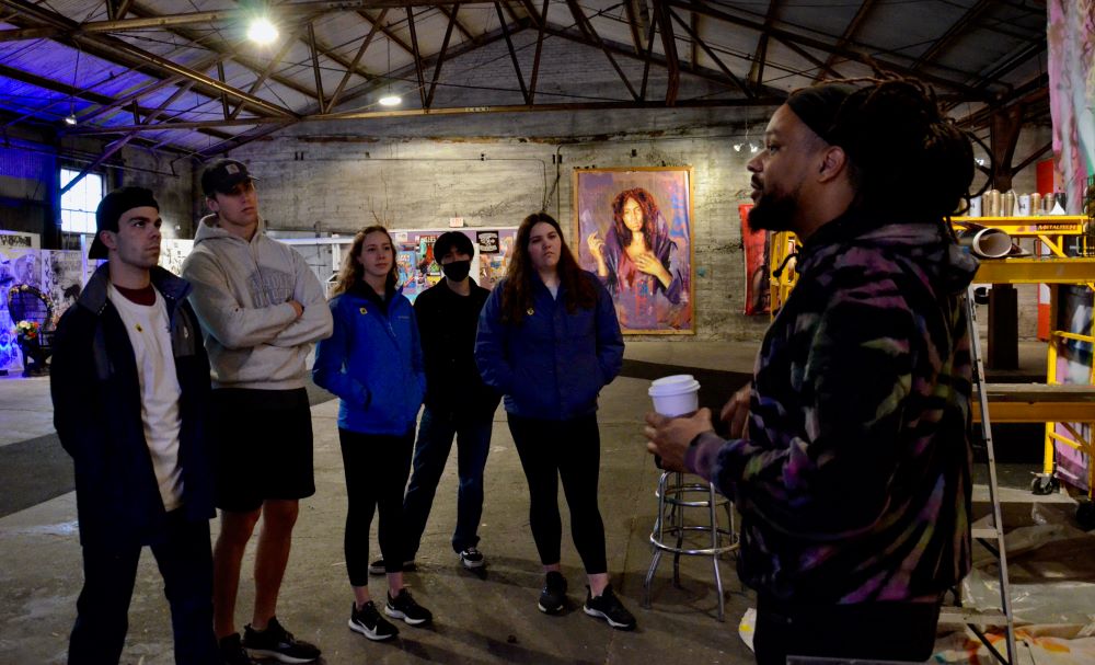Students from Creighton University on a mission trip to New Orleans talk with street artist BMIKE Odums, right, at his studio in the Bywater neighborhood. (GSR photo/Dan Stockman)