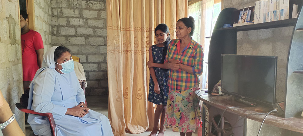 Sr. Shiroma Kurumbalapitiya, Salvatorian provincial in Sri Lanka, with Mary Margaret, far right, a beneficiary of the housing project, and her niece in their new home. Her son is standing in the doorway behind the sister. (Thomas Scaria)