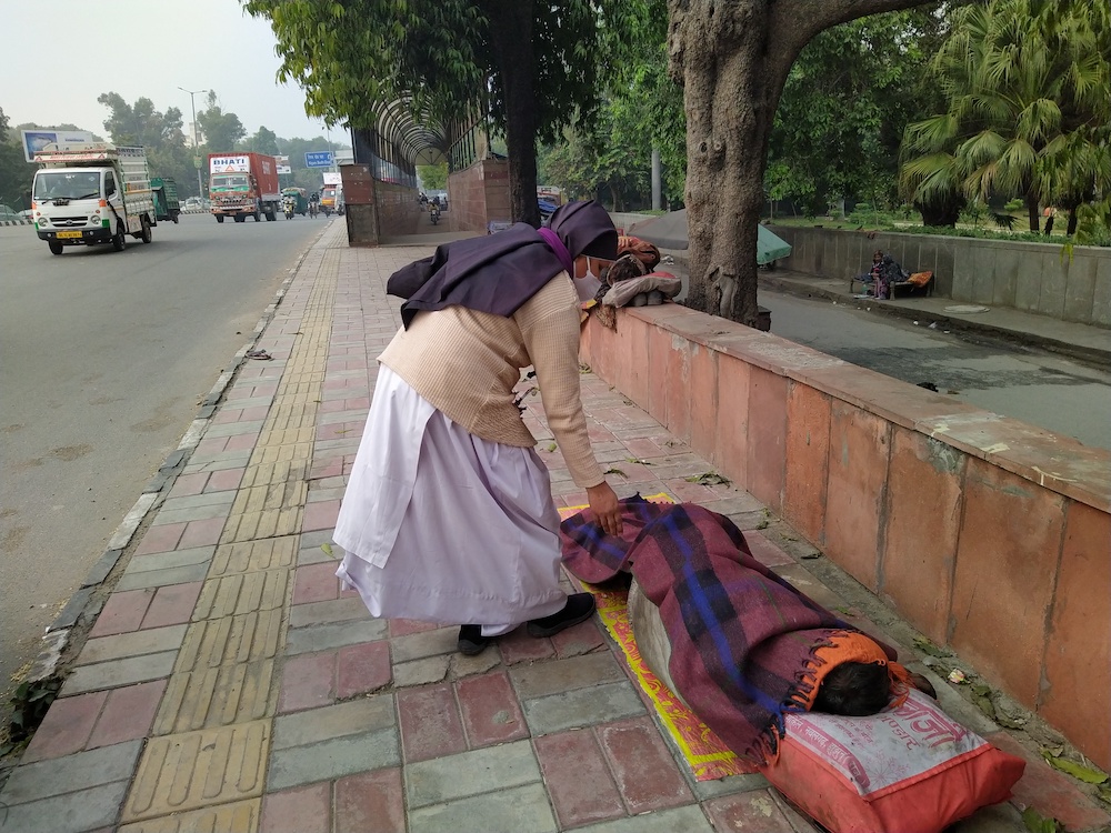 Sr. Preetha Varghese, a member of the Sisters of Imitation of Christ, covers a person sleeping on the pavement of the streets of New Delhi. (Jessy Joseph) Sr. Preetha Varghese, a member of the Sisters of Imitation of Christ, covers a person sleeping on the pavement of the streets of New Delhi. (Jessy Joseph)