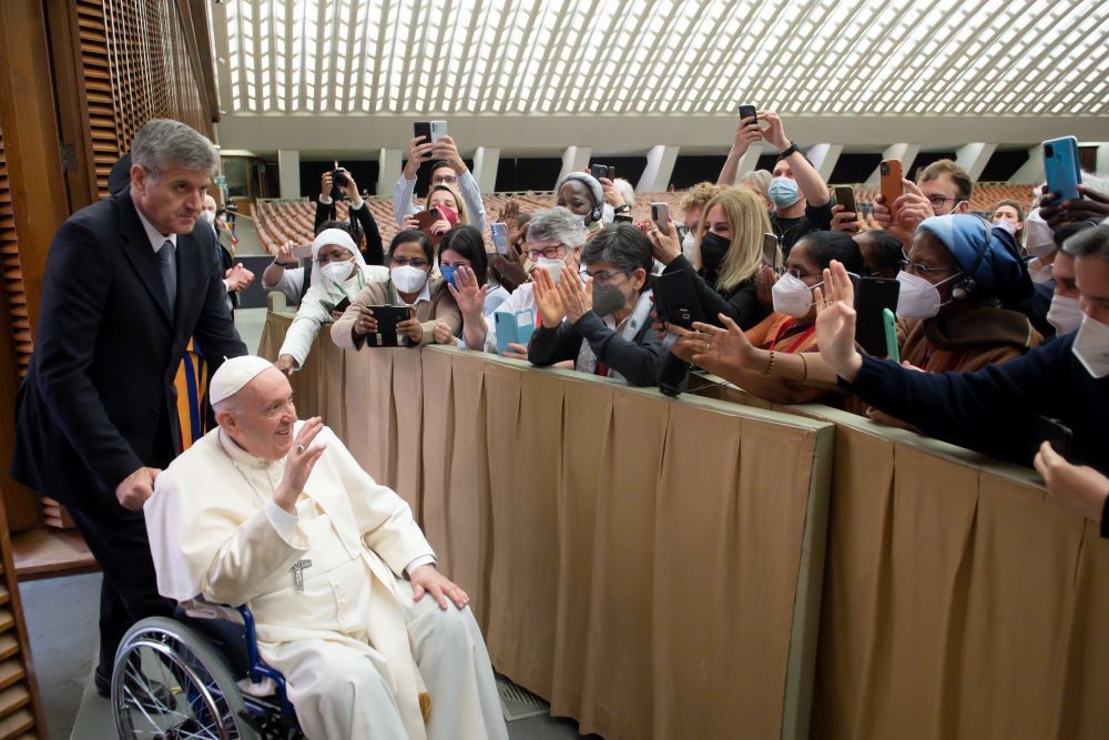Pope Francis is pushed in a wheelchair by his aide, Sandro Mariotti, as he greets participants in the plenary assembly of the International Union of Superiors General on May 5 at the Vatican. (CNS/Vatican Media)