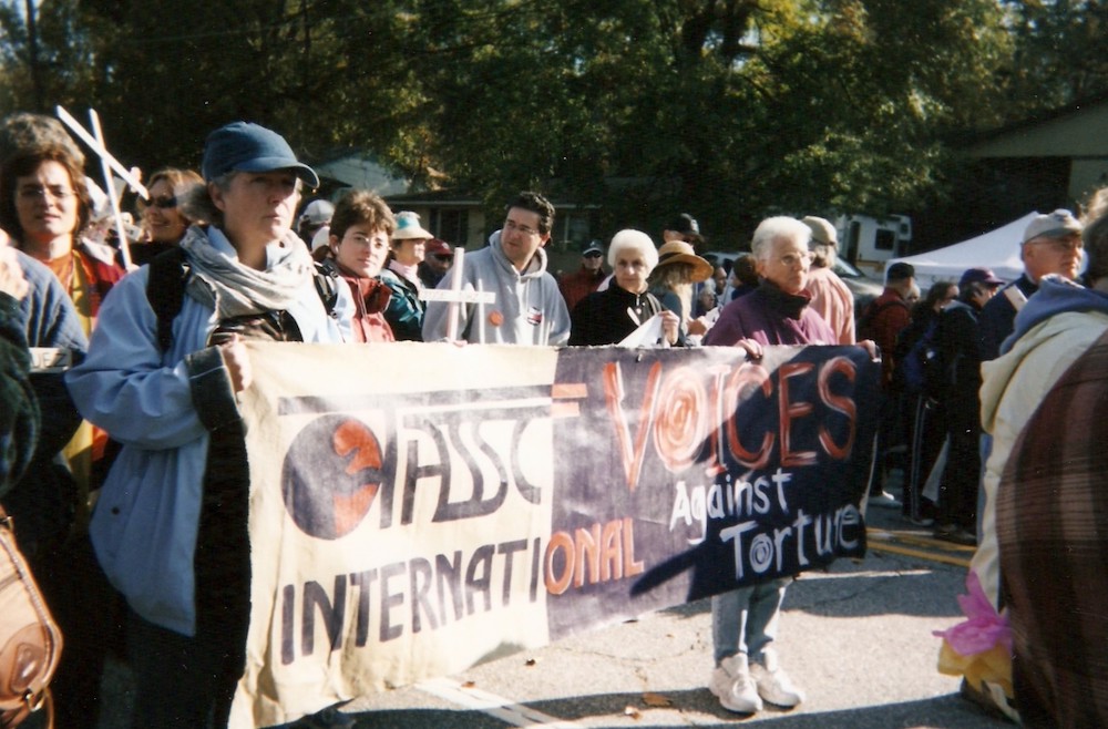 Carrying a banner for the Torture Abolition Survivors Support Coalition, Carmelite Sr. Maureen Foltz, left, in the blue baseball cap, protested the School of Americas in Fort Benning, Georgia for several years. (Provided photo)