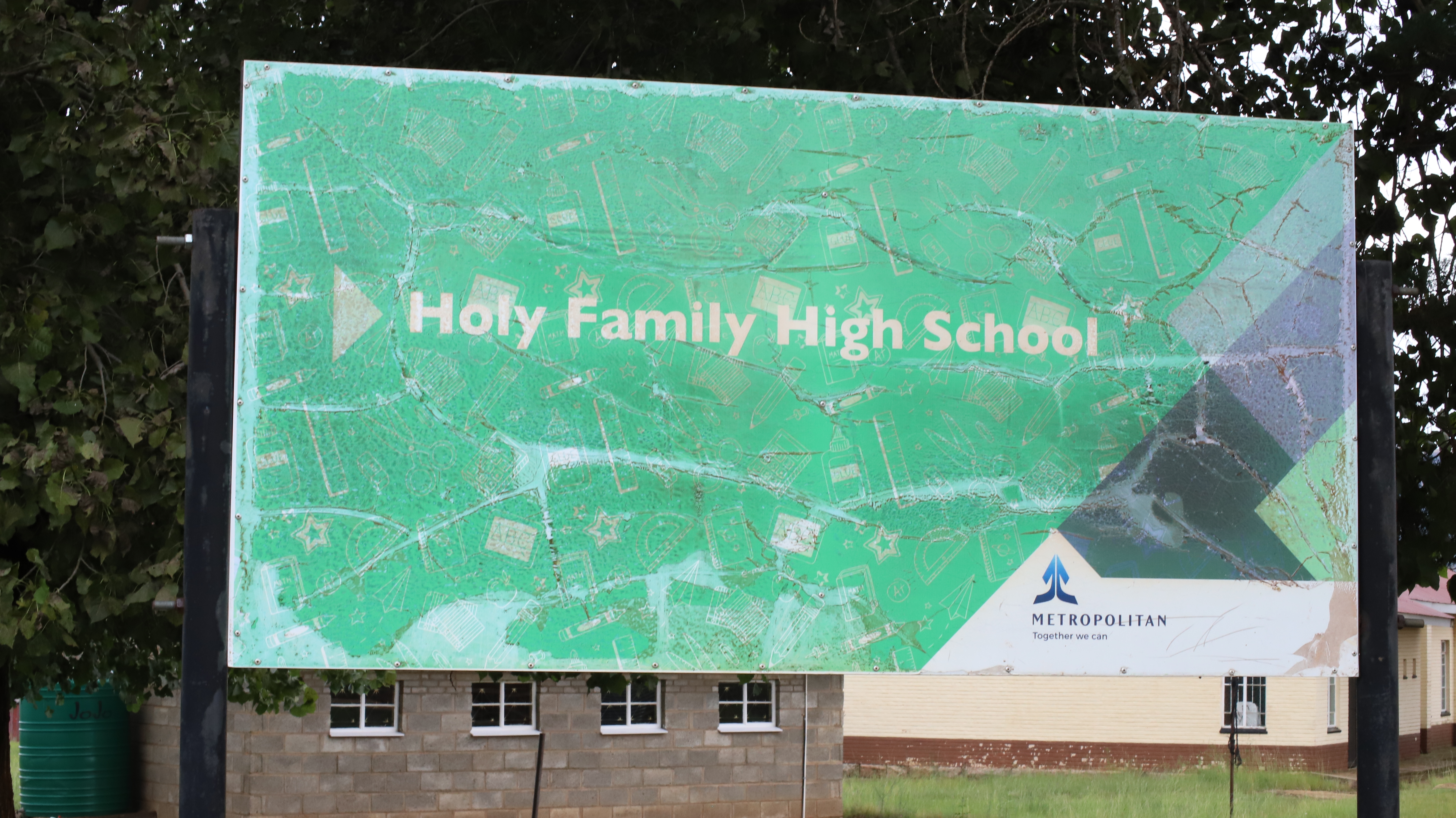 Holy Family High School sign, Lesotho: The sewing project that Sr. Victoria Mota started is located at Holy Family High School in Leribe, Lesotho. She started the sewing project in 2015 to empower youths and ensure they come out of poverty. 