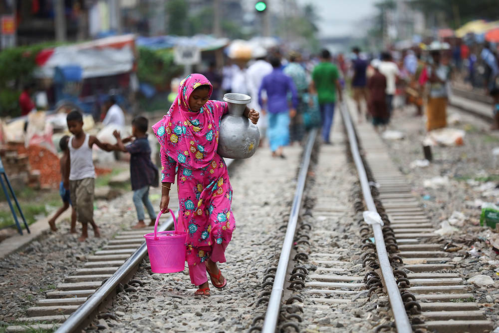 A woman carries drinking water along railroad tracks in a poor section of Dhaka, Bangladesh, Sept. 15, 2020. (CNS/Reuters/Mohammad Ponir Hossain)