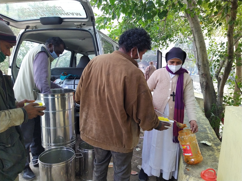 Sr. Preetha Varghese of the Sisters of Imitation of Christ distributes food on the banks of Yamuna River, where thousands of migrants live in garbage dumps. (Jessy Joseph)