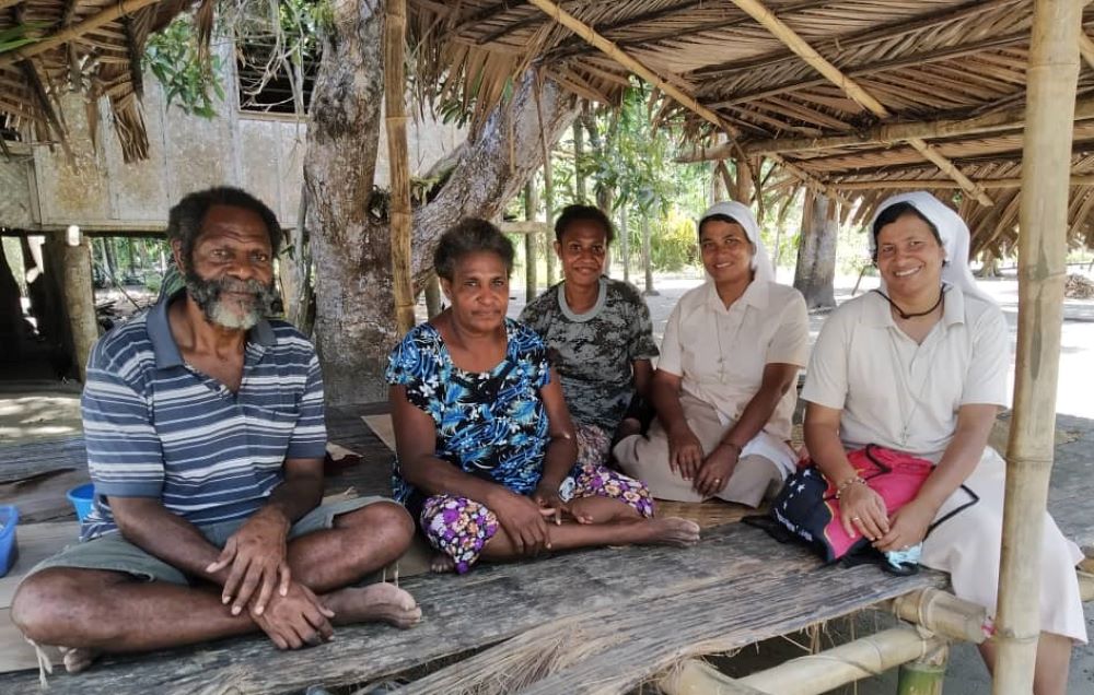 La Hna. Shephali Khalko, congregada en las Hermanas Misioneras de la Inmaculada (segunda por la derecha), visita a una familia con otra monja de la provincia del Golfo en Papúa Nueva Guinea.