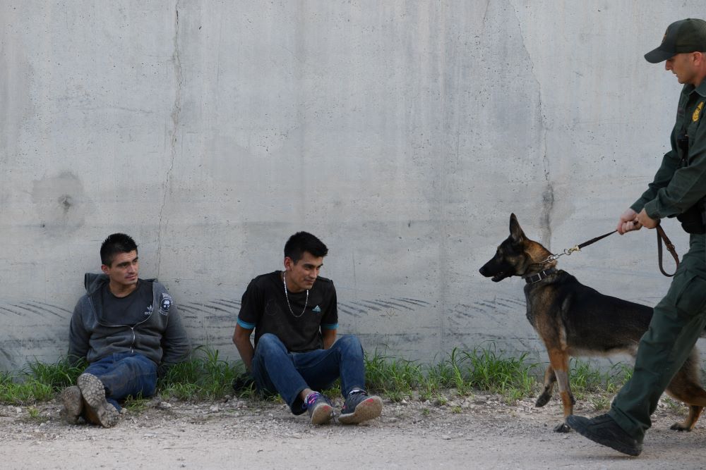 Migrants sit against a levee wall after being apprehended by U.S. Border Patrol agents near Penitas, Texas, on Oct. 8, 2019, after they entered the United States illegally. (CNS/Reuters/Loren Elliott)