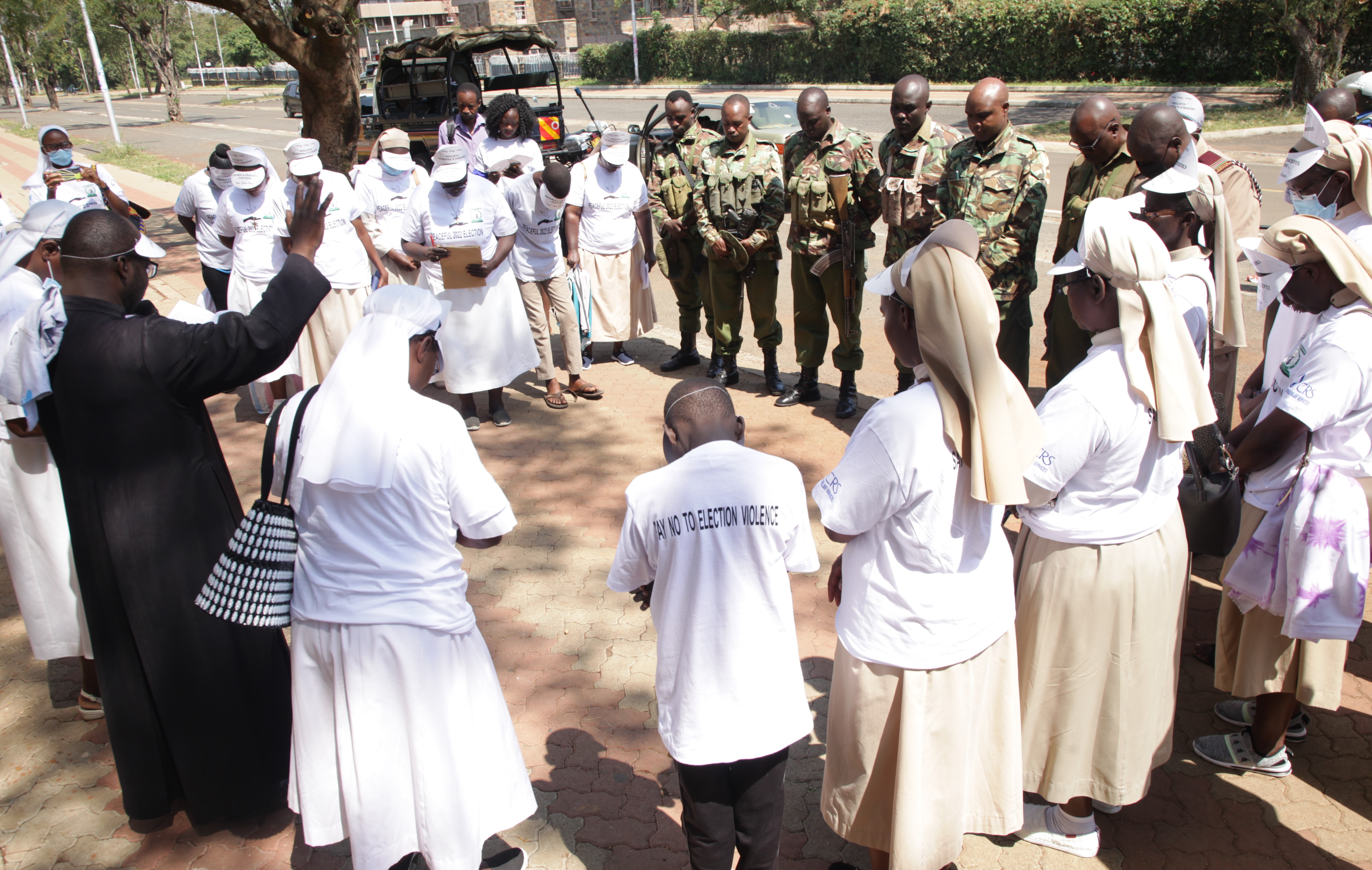 Fr. Shadrack Malo blesses the security officers and Franciscan Sisters of St. Anna in preparation for their peace campaign July 16. The caravan moved around Kisumu town and neighboring towns in Kenya to sensitize people to peaceful elections.