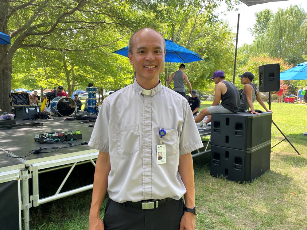 Fr. Timothy Thang Tran of the Congregation of the Mother of the Redeemer stands at the Youth Rally venue. He is the public affairs official for the congregation's organizing committee. (Peter Tran)
