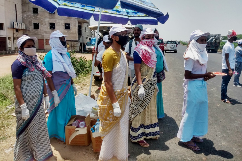 Loreto Srs., from left, Nirmala Toppo, Sawanti Lakra, Jiwanti Tete, Rajini Lugun and Gloria Lakra wait in scorching heat with food packets for migrant laborers on the move at a national highway stop. (Provided photo)