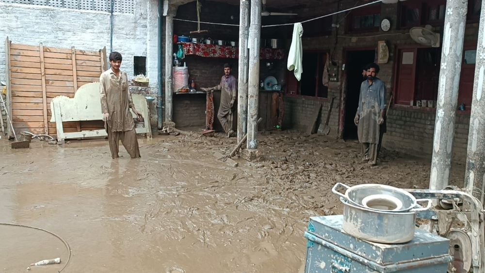 Mohammad Zahid (right) and his brothers look at his house in northern Pakistan's Swat Valley. "Within seconds, we were submerged in 4 to 5 feet of water," Zahid said. "I had to break the walls with a hammer to evacuate the family." (Amjad Gulzar)