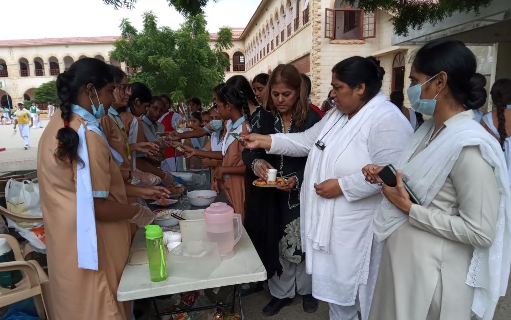 Daughter of the Cross Sr. Elizabeth Niamat (second from right) works at a Sept. 1 bake sale raising funds for the flood victims. She has encouraged families and school staff to donate to a fund to help people affected by the floods. (Courtesy of Elizabeth