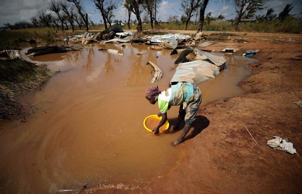 A woman in Mozambique collects water for washing as floodwaters begin to recede in the aftermath of Cyclone Kenneth in 2019. The cyclone's challenges added to the instability of the country beset with Islamist militants. (CNS/Reuters/Mike Hutchings)