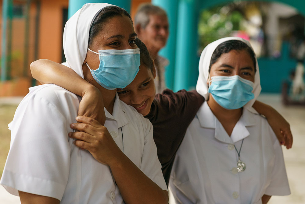 Srs. Jessica Karina Lemus Sánchez and Ana Felipa Olvera Pérez of the Missionaries of Mary Immaculate in Choloma, Honduras, with a young girl whose displaced family is living in the mission's nursery school rooms. (Gregg Brekke)