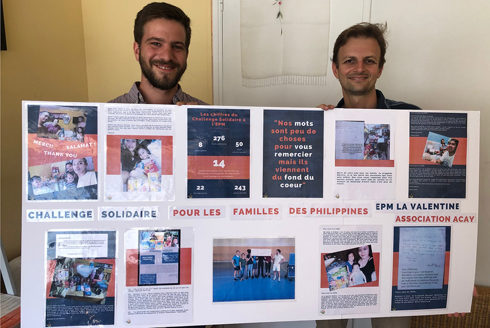 Hubert de la Touche, left, youth accompaniment and training officer for ACAY France, and Laurent Thorigné, right, hold a poster that shows messages from Filipinos thanking French participants in a charity run in May. The run raised money for those in the 