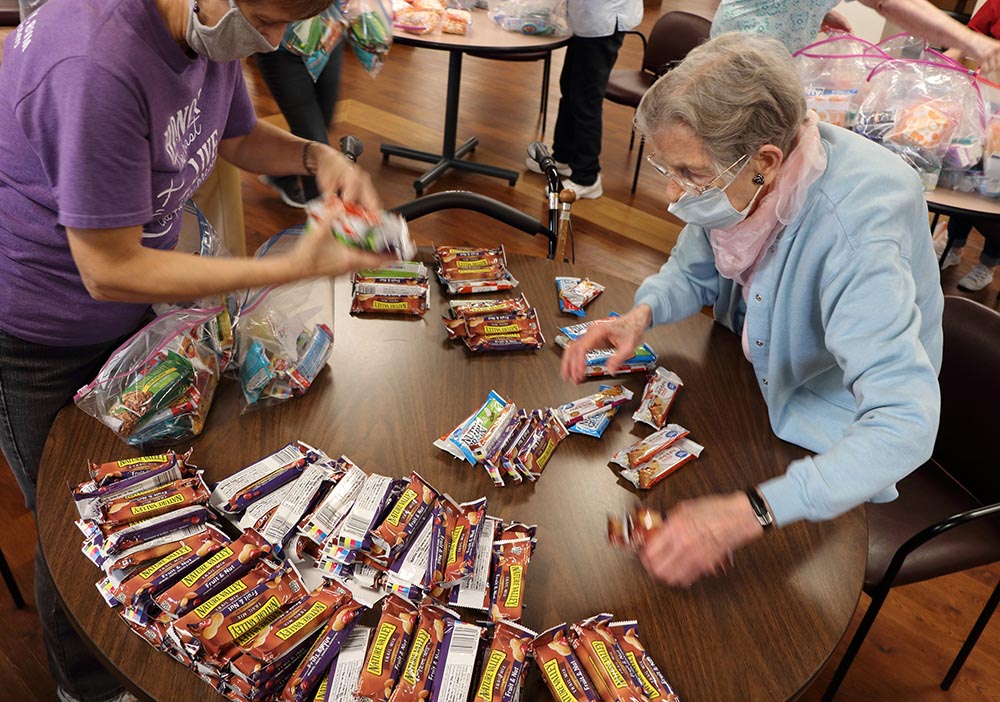Sisters of Charity of the Blessed Virgin Mary staff member Kathy Day and Sr. Pat Donahoe staff the snack bar table in assembling welcome backpacks for Afghan refugees in September at Mount Carmel Bluffs in Dubuque, Iowa.