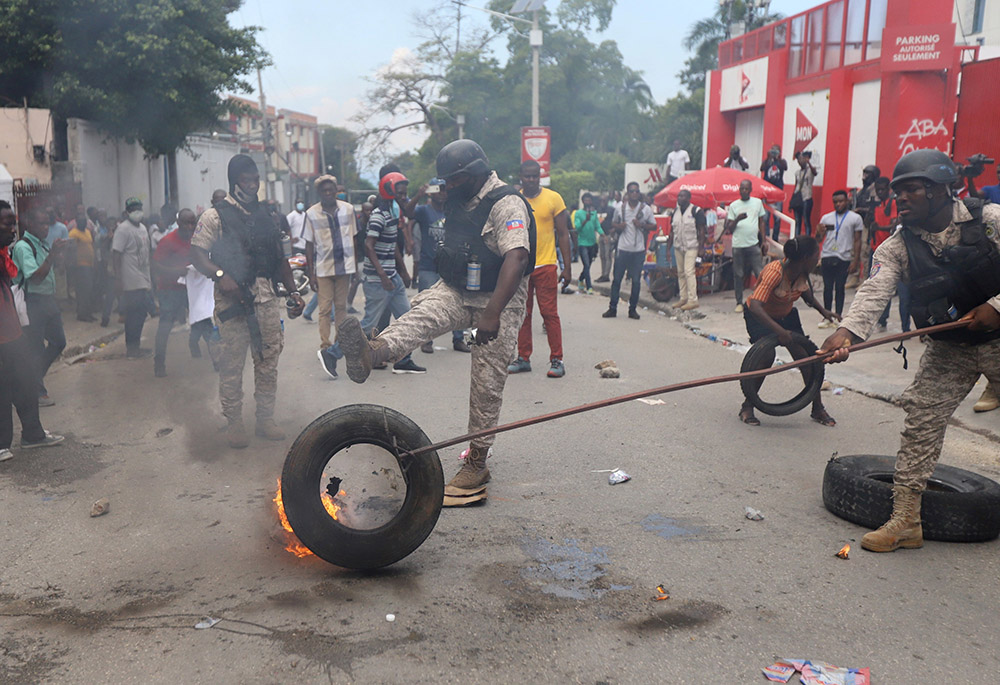 Police in Port-au-Prince, Haiti, remove a burning tire Oct. 18, 2021, as people mount a nationwide strike to protest a growing wave of kidnappings. (CNS/Reuters/Ralph Tedy Erol) Police in Port-au-Prince, Haiti, remove a burning tire Oct. 18, 2021, as people mount a nationwide strike to protest a growing wave of kidnappings. (CNS/Reuters/Ralph Tedy Erol)