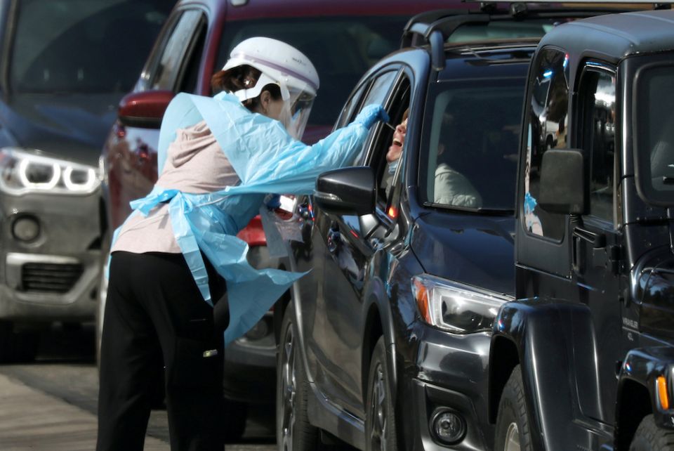 A health care worker in Denver tests people for the coronavirus at a drive-thru testing station March 11. 