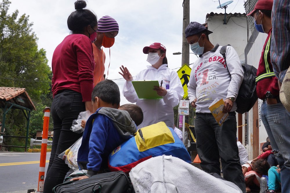 Humanitarian worker Angie Rincon speaks with Venezuelan migrants in early October 2020, at the entrance to Pamplona, Colombia. Rincon is leading a project for migrants funded by Caritas France. (CNS/Manuel Rueda)