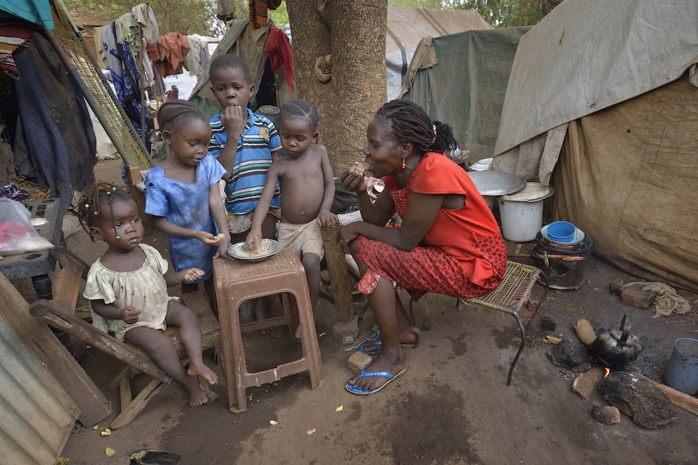 A mother and her children eat a meal at a camp for internally displaced persons on the grounds of St. Mary Catholic Cathedral April 24, 2017, in Wau, South Sudan. Drought and armed conflict pushed tens of thousands of Wau-area residents out of their homes