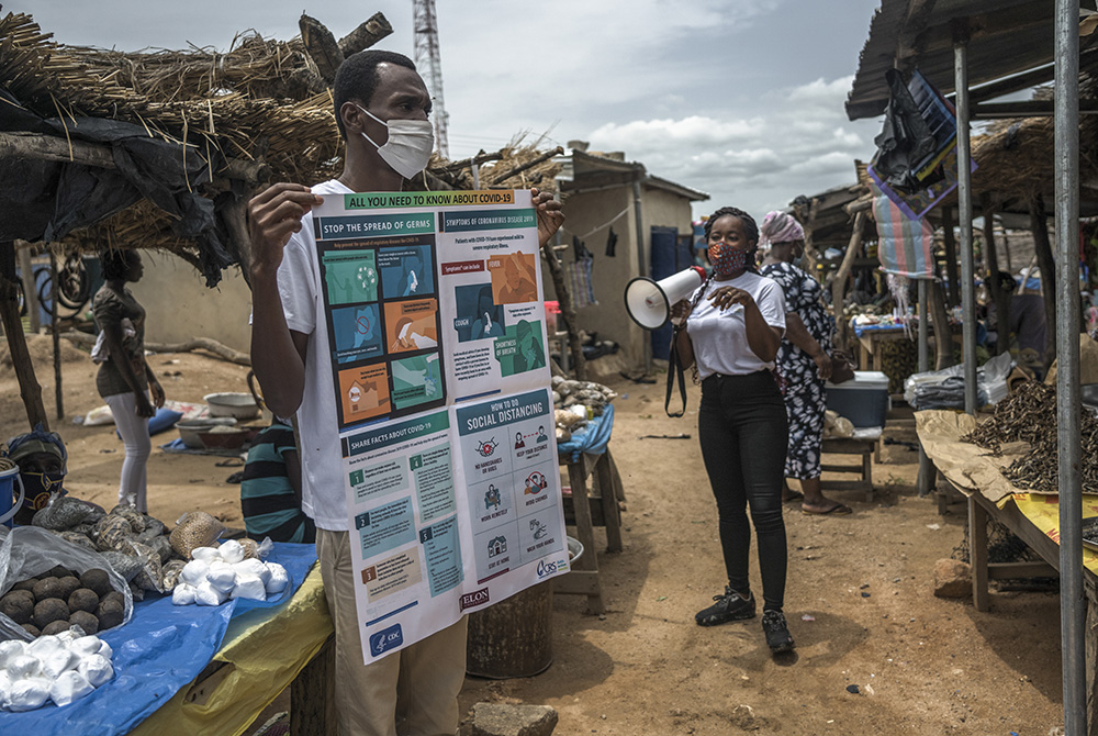 Catholic Relief Services field workers carry out COVID-19 "sensitization" efforts at the market in Pwalugu, Ghana, in June 2020. The city, located in the Upper East region of northern Ghana, has been the epicenter of the pandemic in the region. (CRS photo