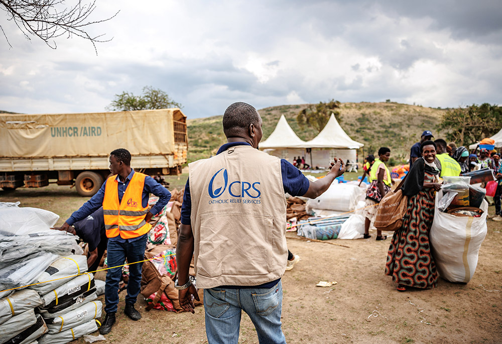 A Catholic Relief Services distribution in Nakivale Refugee Settlement in Uganda. Refugees received a startup kit including shelter tarpaulin, poles, ropes, blankets, a net, mats, a solar lamp and a kitchen set. (Courtesy of Catholic Relief Services)
