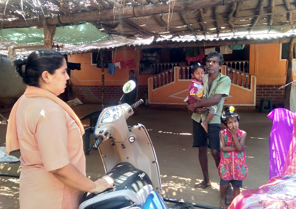 Sr. Crina Cardozo of the Sisters of Holy Family of Nazareth talks to the husband of a tribal woman in Karvem village of Goa, western India. (Lissy Maruthanakuzhy)