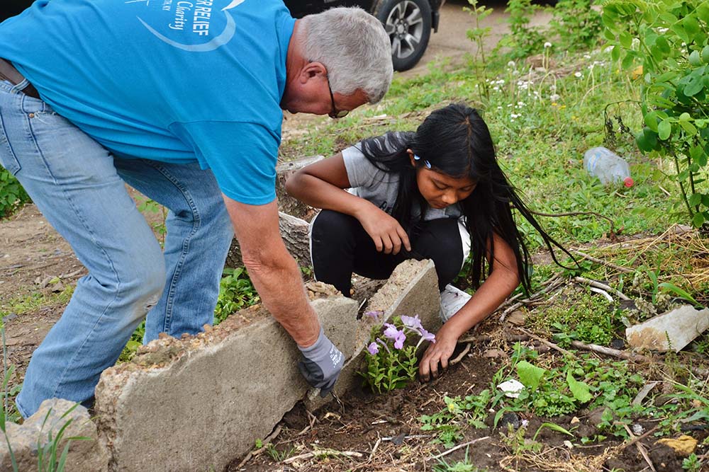 David White, a volunteer with the Sisters of Charity of Nazareth's disaster recovery team, plants flowers May 23 with one of the children whose home was damaged by a Dec. 10 tornado in Mayfield, Kentucky. (GSR photo/Dan Stockman)