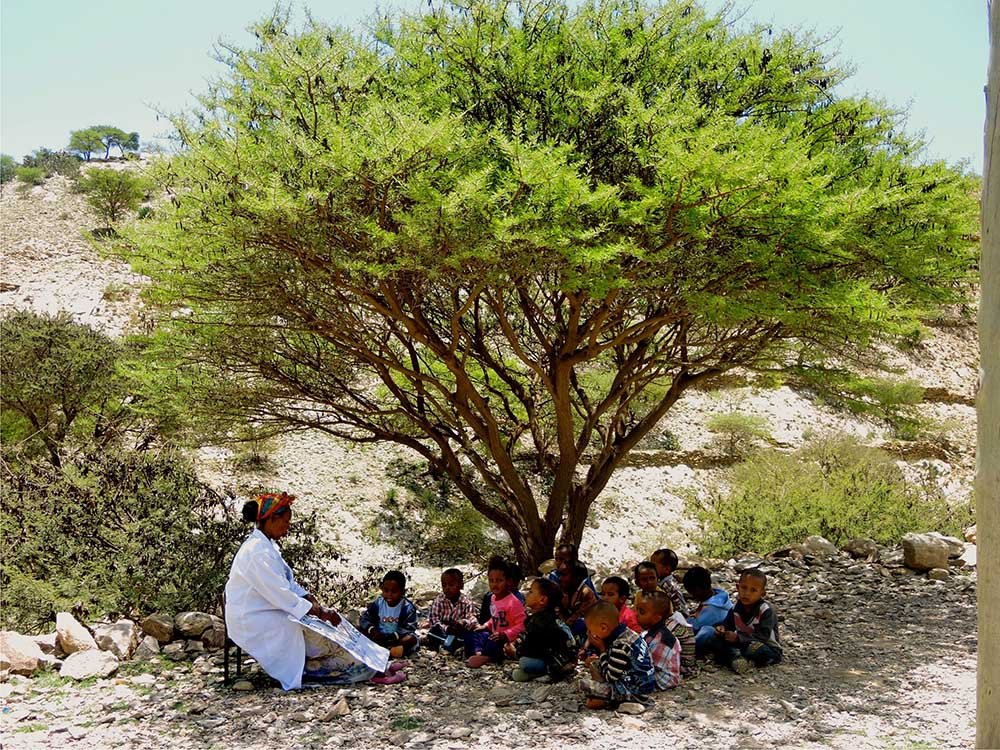 A teacher gives a lesson to kindergartners under a tree in the courtyard of the school in Dawhan, Ethiopia, in 2016. (GSR photo/Melanie Lidman) A teacher gives a lesson to kindergartners under a tree in the courtyard of the school in Dawhan, Ethiopia, in 2016. (GSR photo/Melanie Lidman)