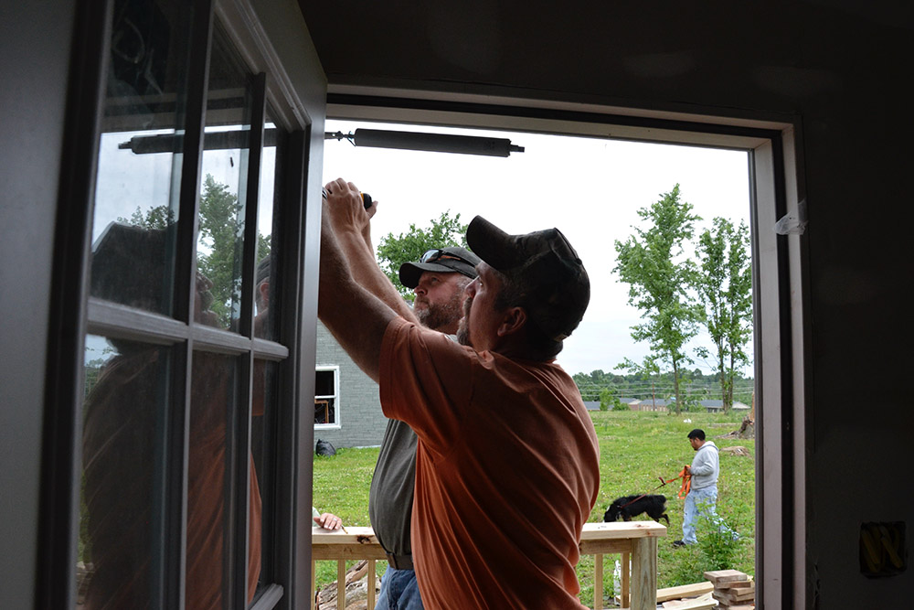 Eric Shelburne, left, and Ronnie Mattingly install a storm door May 23 at a house damaged by a tornado in Mayfield, Kentucky. (GSR photo/Dan Stockman)
