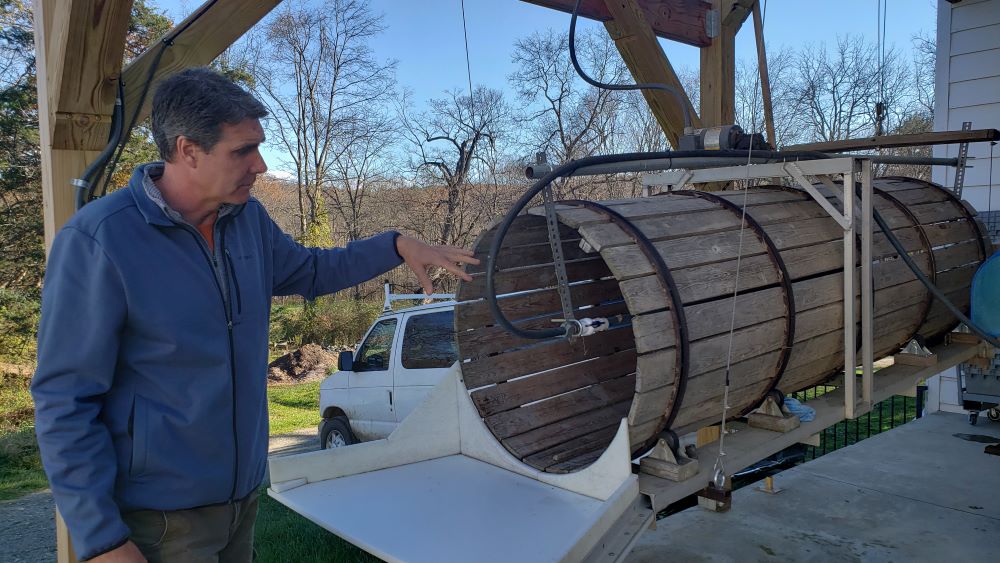 Sisters Hill Farm Director David Hambleton demonstrates a root washing machine — sometimes called a barrel washer — used to wash root crops like carrots. (Chris Herlinger)