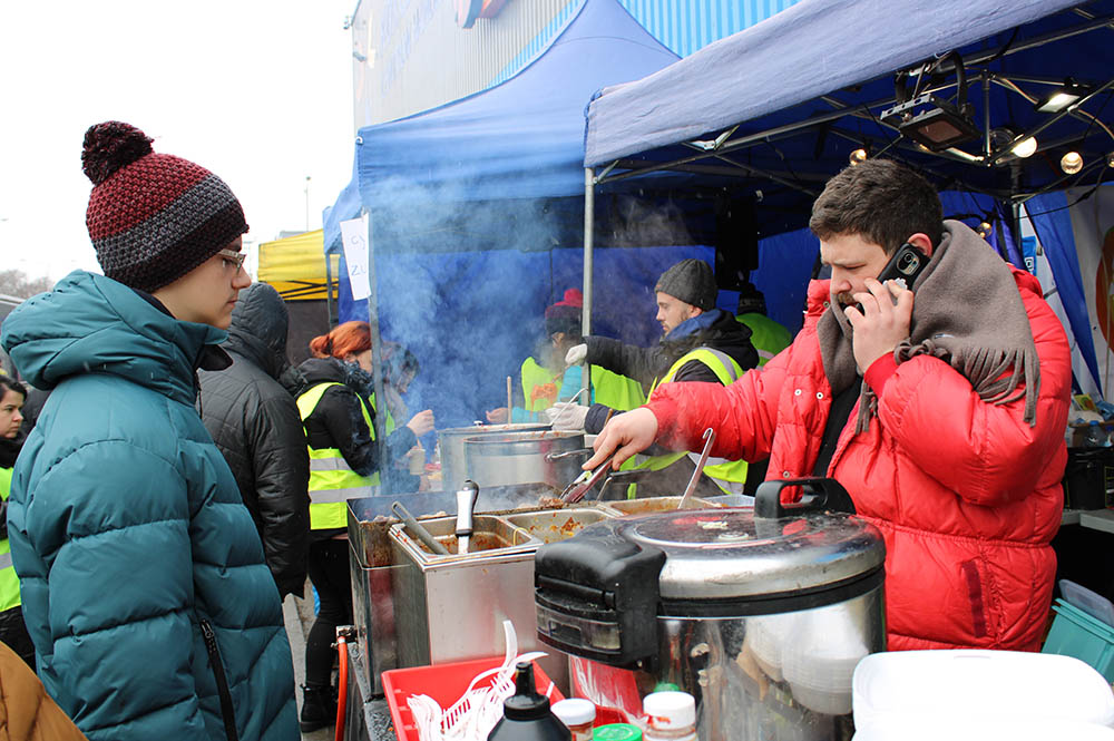 A volunteer prepares food for Ukrainian refugees at a stall outside a refugee transit site in Korczowa, Poland. (GSR photo/Chris Herlinger)