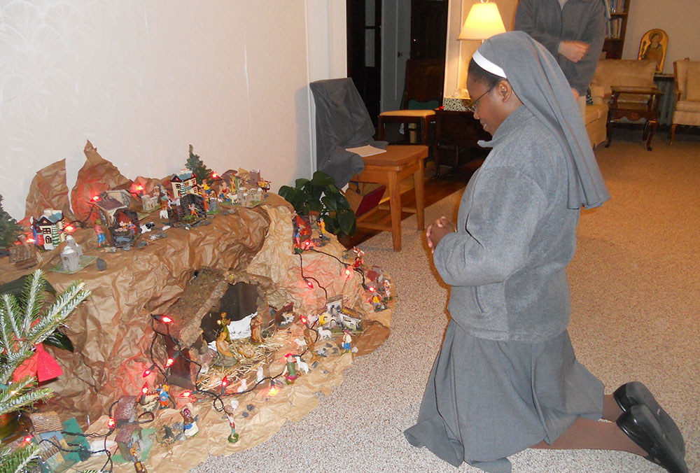 Sr. Dorcas Cordilia Munthali of the Franciscan Missionary Sisters of Assisi, who ministers in Brooklyn, New York, kneels to pray before the crèche at St. Francis Convent, Holyoke, Massachusetts, during the Christmas gathering in 2018. (Provided photo)