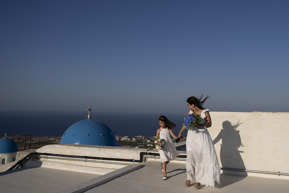 Cinzia Sansone and her daughter Josephine, from Trieste, Italy, pose for photos on a rooftop overlooking the Catholic Monastery of St. Catherine on the Greek island of Santorini June 14. (AP/Petros Giannakouris)