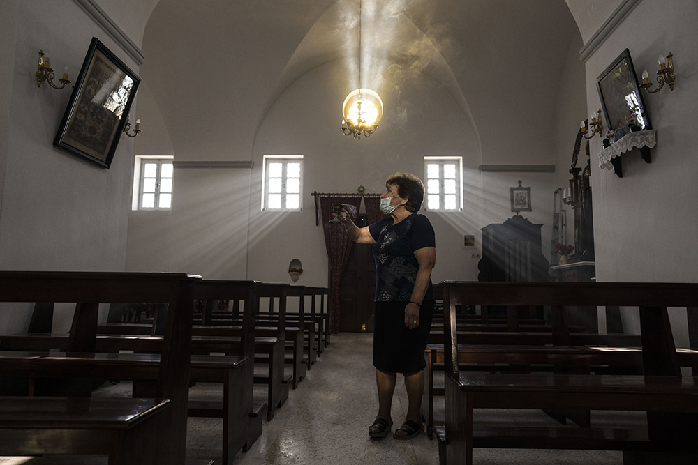 Parishioner Maria Tsagorari holds an incense burner inside the Dormition of the Virgin Mary Catholic Church on the Greek island of Santorini June 15. Before coronavirus restrictions, she used to attend Mass regularly at the Monastery of St. Catherine. (AP