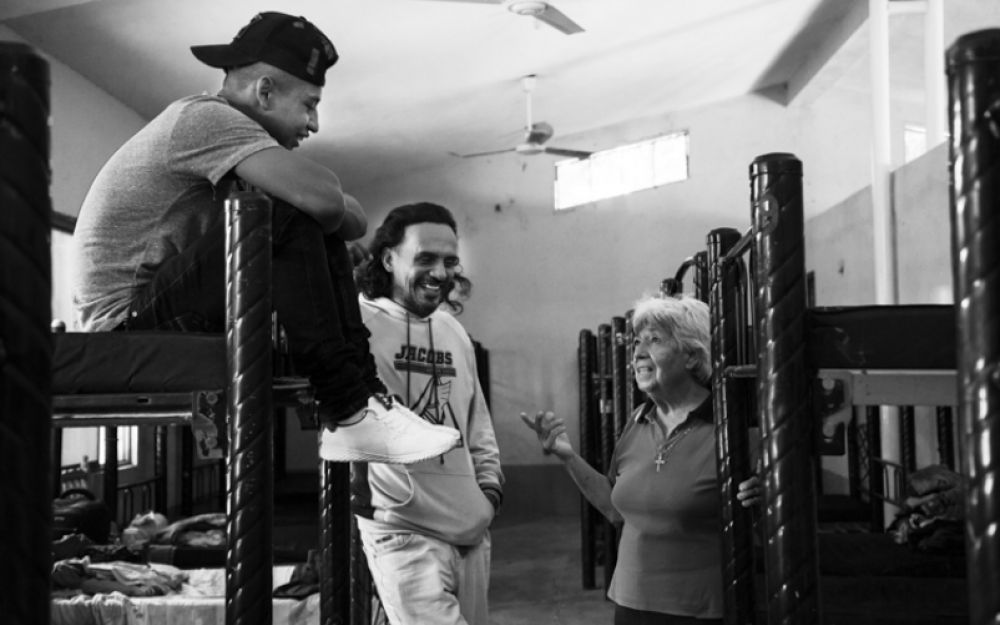 Sr. María Elena Cordero Duarte visits with male migrants in their bunk room at the Albergue Hermanos en el Camino in Ixtepec, Mexico.