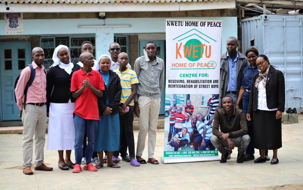 Srs. Caroline Ngatia (at left, in white veil) and Caroline Cheruiyot (far right) and members of the staff work together on behalf of the street children, some of whom are pictured here, at Kwetu Home of Peace in Nairobi, Kenya. (Doreen Ajiambo)