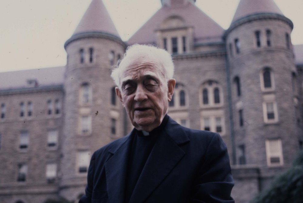 Msgr. John Tracy Ellis, 1905-1992, in front of a stone building