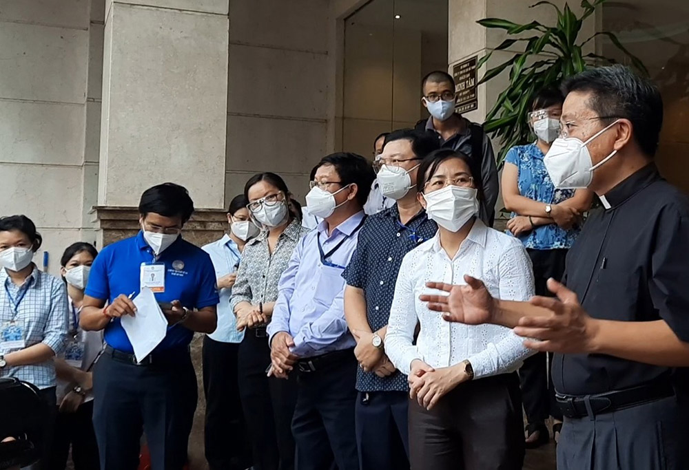 Fr. Joseph Dao Nguyen Vu, right, who represents Vietnam's Ho Chi Minh City Archdiocese, and government authorities welcome religious volunteers to Minh Tam Hotel on Aug. 20. (Joachim Pham)