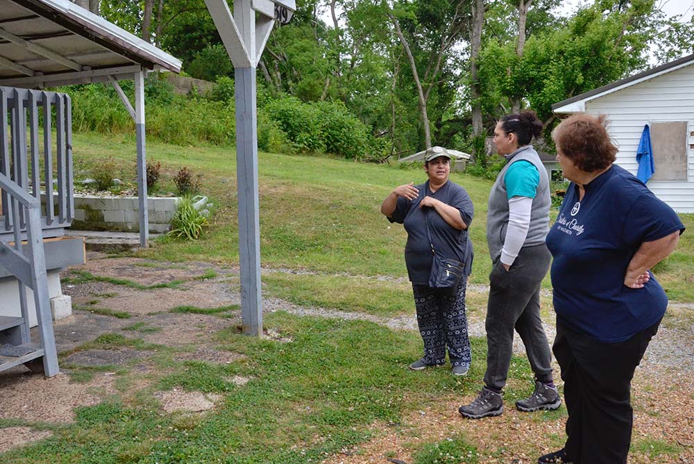 Josepha Casteñeda, left, talks to Catholic Charities of Owensboro, Kentucky, caseworker Kariña Gonzalez, center, and Sr. Luke Boiarski on May 24 about the damage done to her home by a tornado. (GSR photo/Dan Stockman)